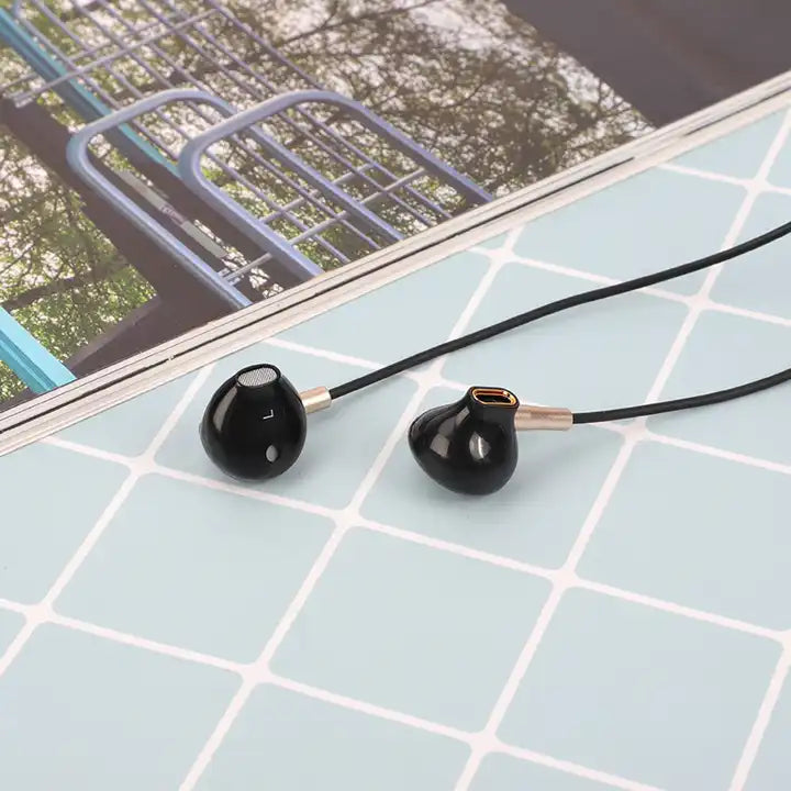 audífono con cable vq-h35 color negro al lado de revista